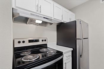 a kitchen with white cabinets and black appliances and a refrigerator